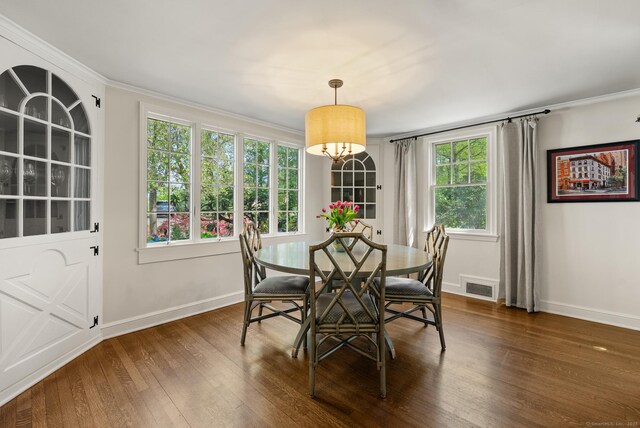 dining area featuring dark wood finished floors, visible vents, baseboards, and ornamental molding