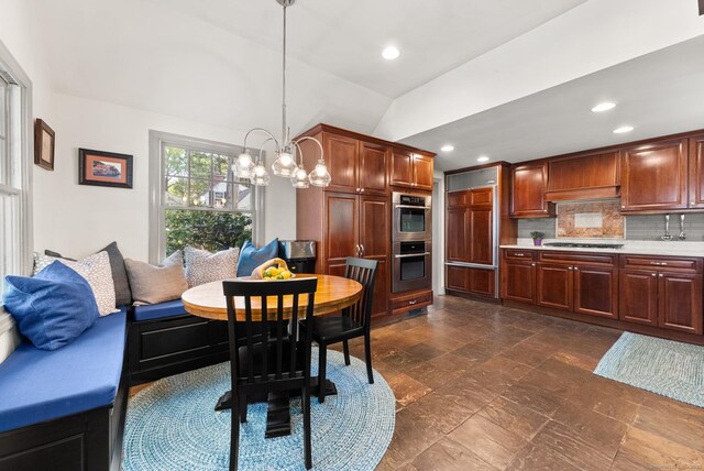 dining space featuring lofted ceiling, a chandelier, recessed lighting, and dark stone finish floors