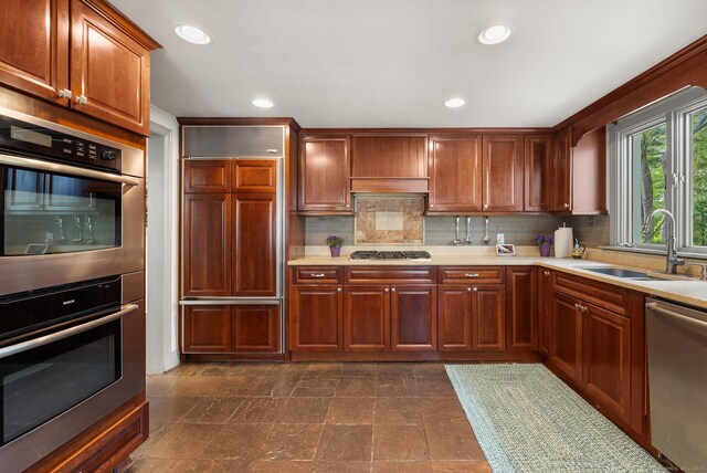 kitchen featuring light countertops, appliances with stainless steel finishes, decorative backsplash, and a sink