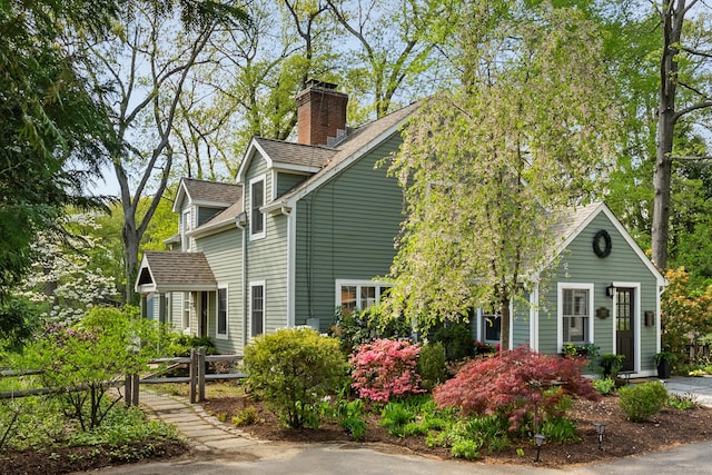 view of property exterior with a chimney and a shingled roof