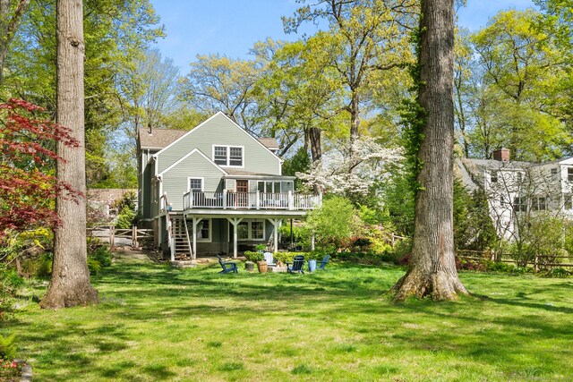 back of property featuring a deck, a lawn, and stairway
