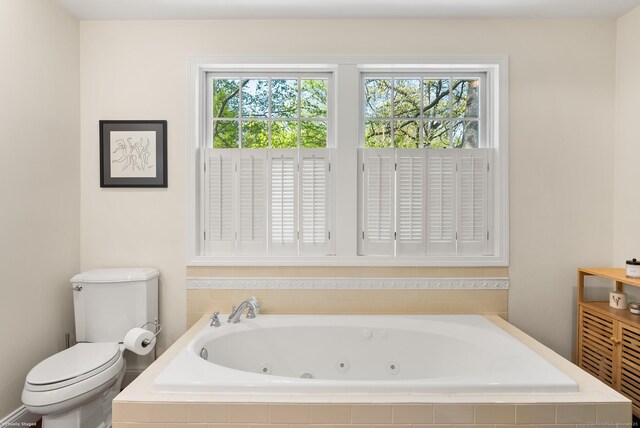 bathroom featuring toilet, a whirlpool tub, and healthy amount of natural light