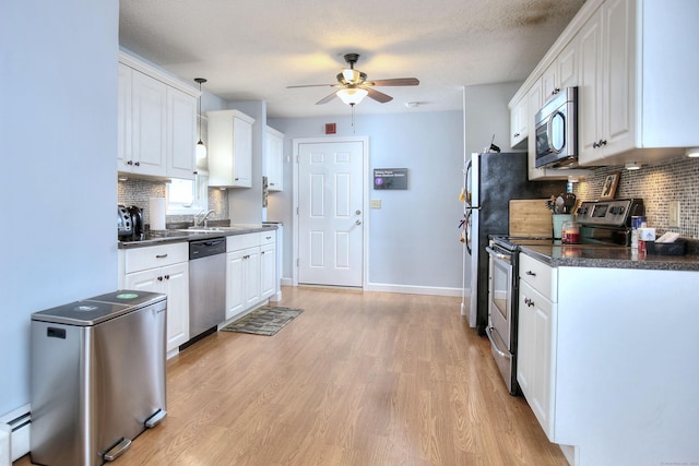 116 Hill St Unit 23, Milford, CT 06460 - kitchen with dark countertops, white cabinetry, a ceiling fan, light wood-style flooring, and stainless steel appliances
