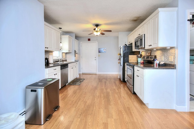 116 Hill St Unit 23, Milford, CT 06460 - kitchen featuring dark countertops, ceiling fan, white cabinetry, light wood-style flooring, and appliances with stainless steel finishes