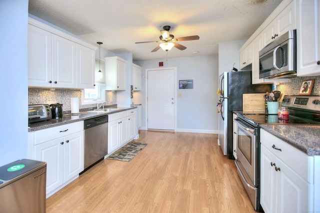116 Hill St Unit 23, Milford, CT 06460 - kitchen with ceiling fan, decorative backsplash, appliances with stainless steel finishes, white cabinets, and light wood-style floors