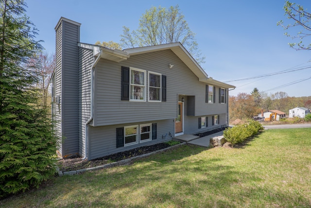 split foyer home with a chimney and a front lawn