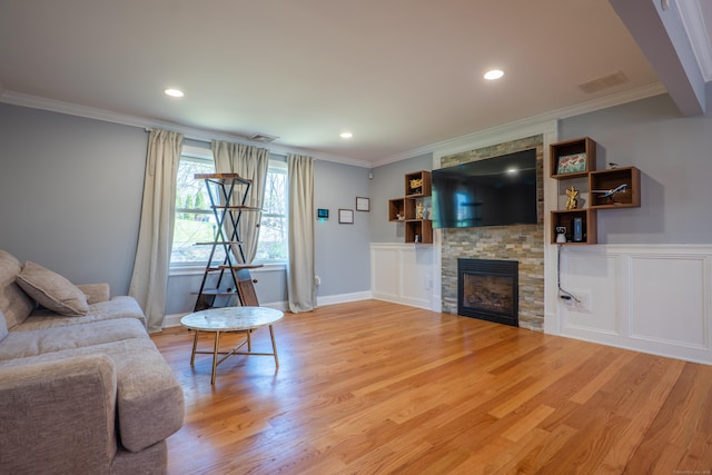 living room with ornamental molding, a stone fireplace, wood finished floors, and recessed lighting