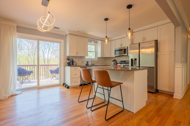 kitchen with appliances with stainless steel finishes, white cabinets, light wood-style floors, tasteful backsplash, and ornamental molding
