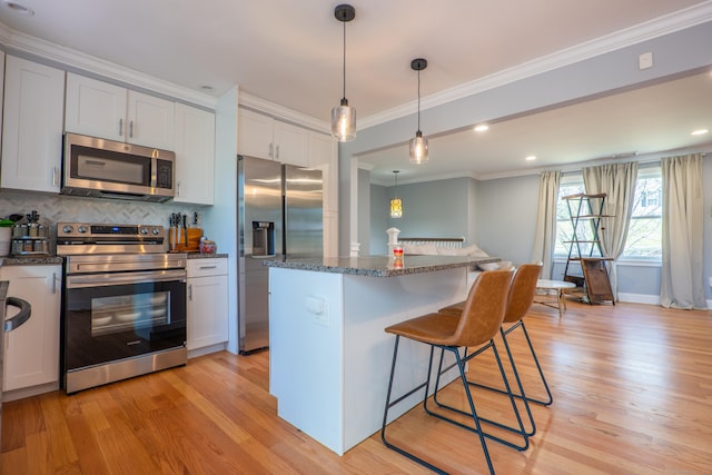 kitchen with stainless steel appliances, crown molding, light wood finished floors, a kitchen breakfast bar, and backsplash