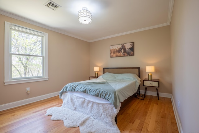 bedroom with wood finished floors, baseboards, and crown molding