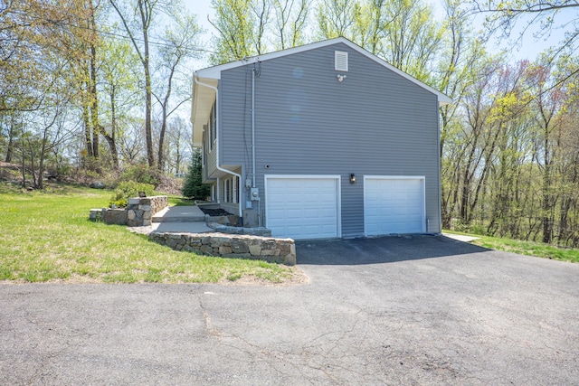 view of property exterior featuring asphalt driveway, an attached garage, and a lawn