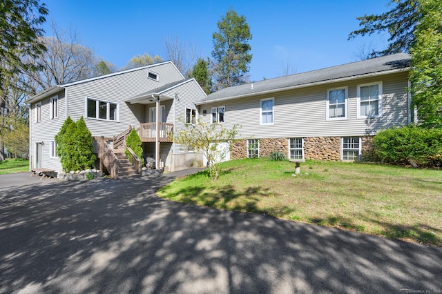 view of front of home featuring aphalt driveway, a front lawn, and stairway