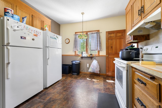 kitchen featuring brown cabinetry, stone finish flooring, light countertops, under cabinet range hood, and white appliances