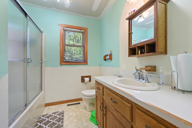 full bath with visible vents, vanity, baseboards, toilet, and enclosed tub / shower combo