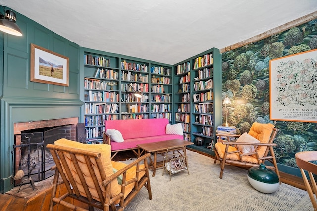 149 Limekiln Rd, Redding, CT 06896 - sitting room featuring wall of books, wood finished floors, a brick fireplace, and built in shelves