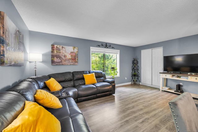 living area featuring wood finished floors, baseboards, and a textured ceiling