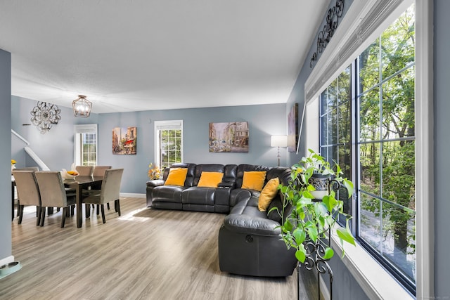living area featuring light wood-style flooring, a chandelier, and baseboards