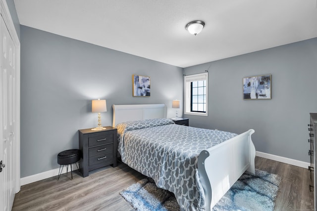 bedroom with wood finished floors, a closet, and baseboards