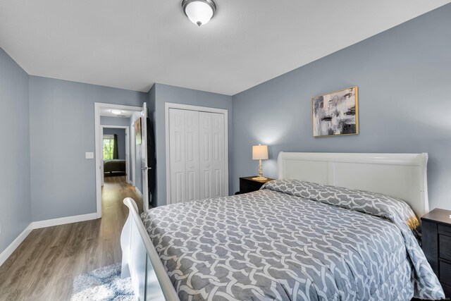bedroom with wood finished floors, baseboards, and a closet