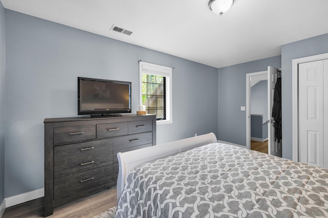 bedroom featuring baseboards, wood finished floors, and a closet