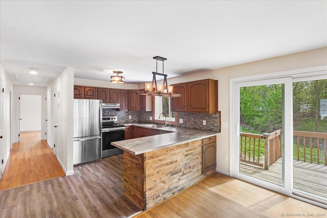 kitchen featuring stainless steel appliances, a healthy amount of sunlight, light wood-style flooring, and a peninsula