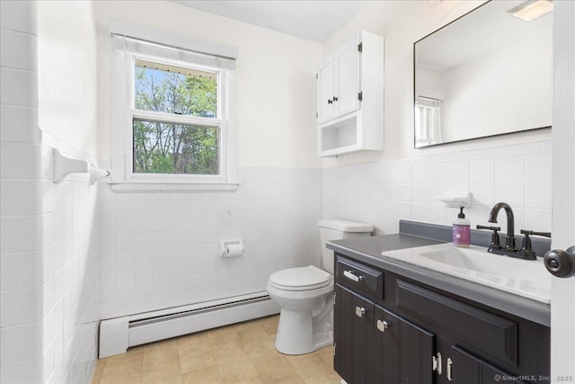 bathroom featuring tile walls, baseboard heating, wainscoting, vanity, and toilet
