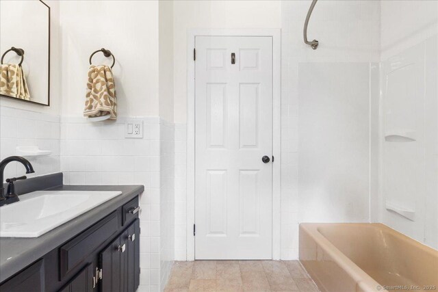 bathroom featuring tile walls, vanity, and bathing tub / shower combination