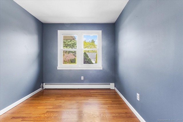 spare room featuring baseboards, light wood finished floors, and a baseboard heating unit