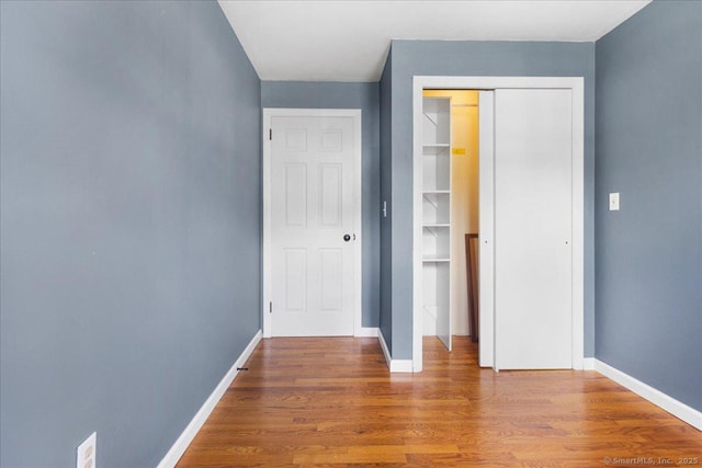 unfurnished bedroom with a closet, baseboards, and wood finished floors