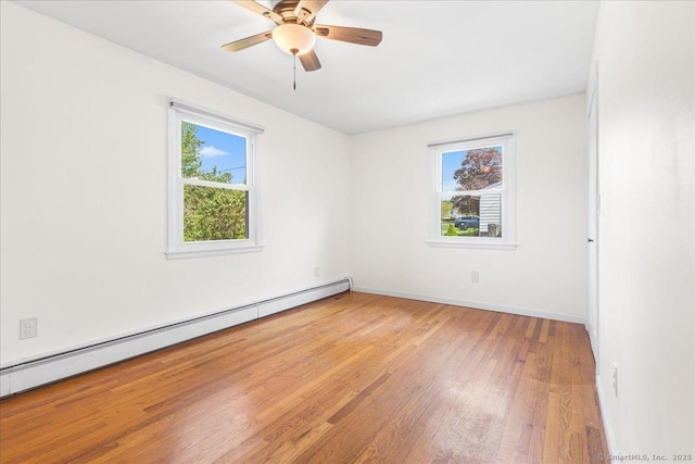 spare room with baseboards, ceiling fan, a baseboard heating unit, and light wood-style flooring