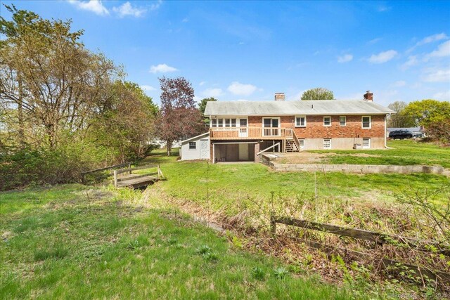 back of property with a lawn, a deck, and a chimney