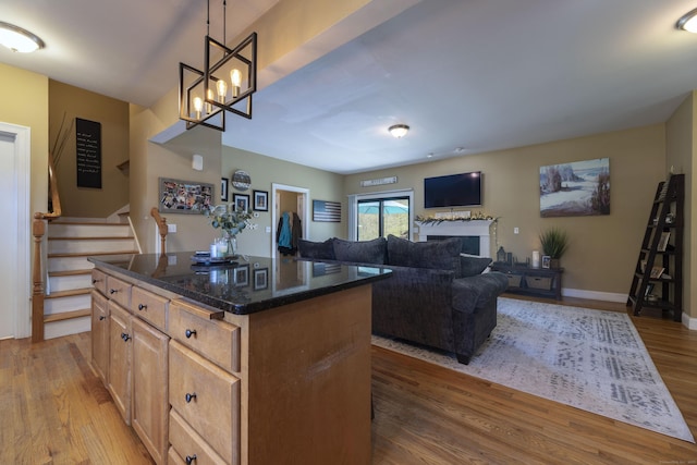 14 Cutter Dr, Stonington, CT 06355 - kitchen with a center island, dark stone countertops, light wood finished floors, a fireplace, and decorative light fixtures