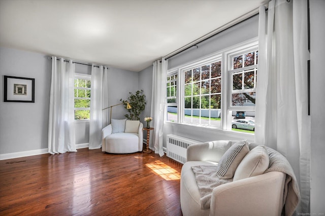 sitting room with radiator, wood finished floors, and baseboards