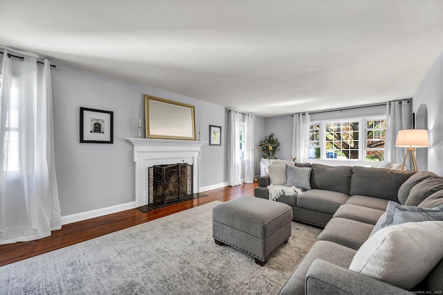 living area featuring wood finished floors, a brick fireplace, and baseboards