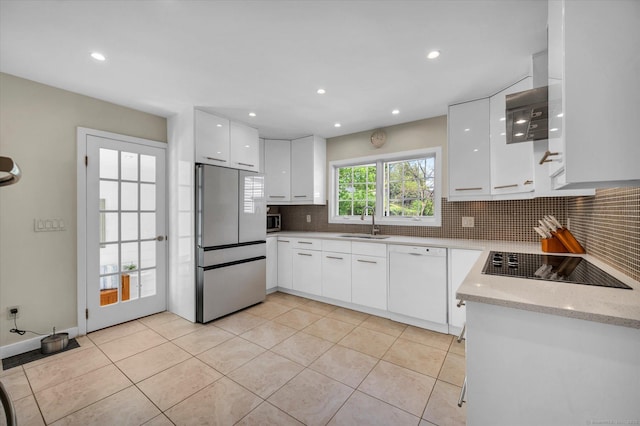 kitchen with appliances with stainless steel finishes, a sink, modern cabinets, backsplash, and white cabinetry