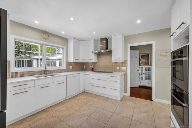 kitchen featuring a sink, wall chimney range hood, dishwasher, double oven, and tasteful backsplash