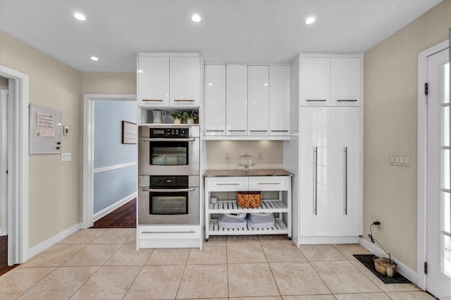 kitchen featuring double oven, white cabinets, baseboards, and recessed lighting