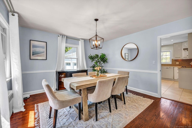dining room featuring a chandelier, light wood-style flooring, and baseboards