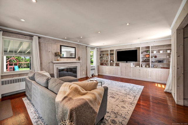 living room featuring radiator heating unit, ornamental molding, a tiled fireplace, wood finished floors, and recessed lighting