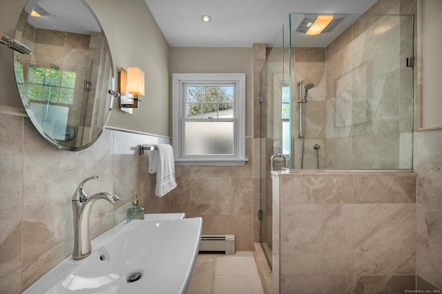 full bathroom featuring a baseboard radiator, tile walls, a shower stall, and a sink