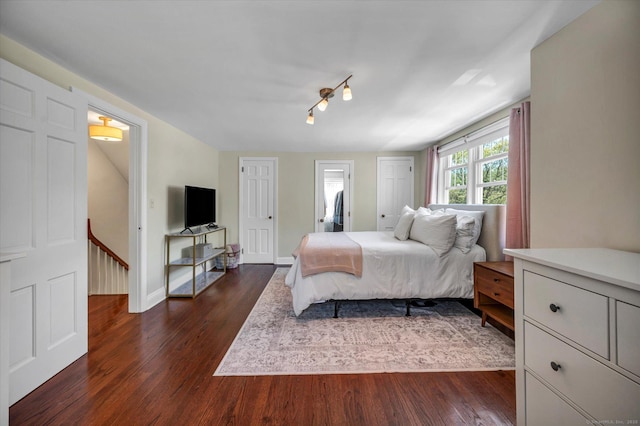 bedroom featuring dark wood-style flooring, rail lighting, and baseboards