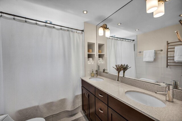 full bath with double vanity, toilet, and recessed lighting
