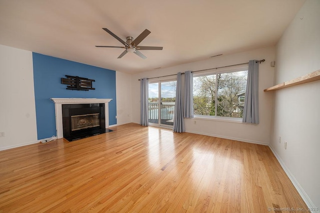 unfurnished living room with a fireplace with flush hearth, baseboards, ceiling fan, and wood finished floors