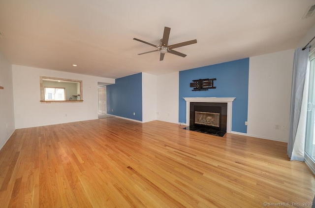 unfurnished living room featuring baseboards, ceiling fan, a tile fireplace, and wood finished floors