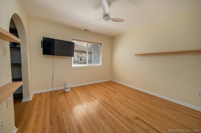 interior space featuring ceiling fan, visible vents, arched walkways, light wood-type flooring, and baseboards