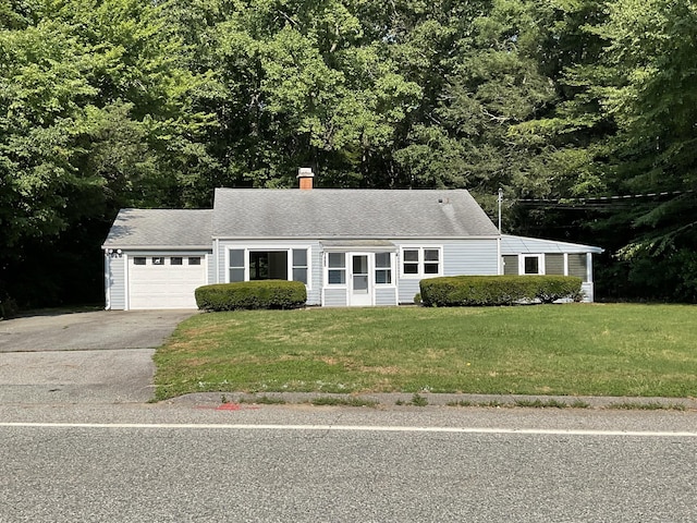 view of front of home featuring a chimney, an attached garage, concrete driveway, and a front yard