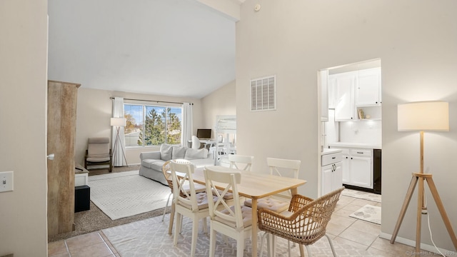 dining space with visible vents, baseboards, light tile patterned floors, and high vaulted ceiling