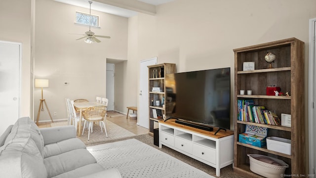 living room with a ceiling fan, a high ceiling, and baseboards