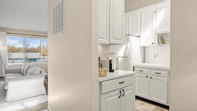 kitchen with light countertops, tasteful backsplash, and white cabinetry