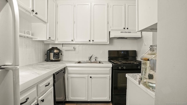 kitchen with freestanding refrigerator, black range with gas stovetop, under cabinet range hood, white cabinets, and a sink